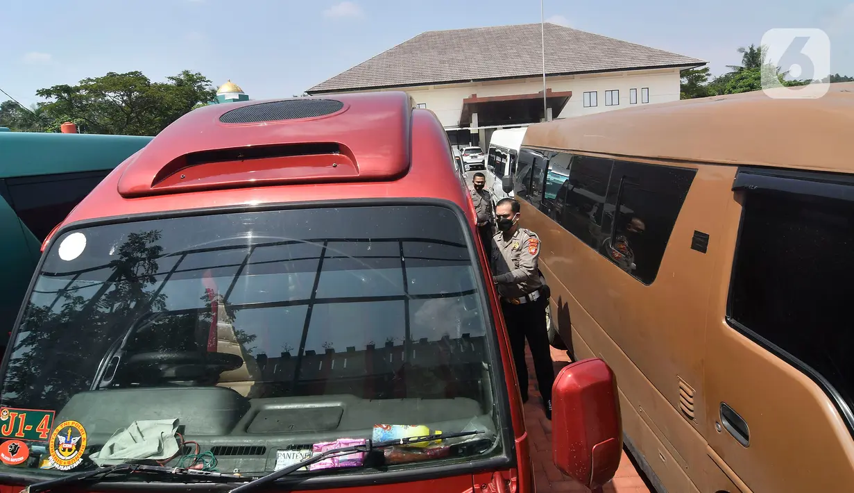 Petugas polisi memeriksa mobil travel gelap yang disita di halaman Polres Metro Kabupaten Bekasi, Jawa Barat, Senin (10/5/2021). Satlantas Polres Metro Bekasi mengamankan 32 travel gelap yang masih beroperasi saat larangan mudik dari tanggal 6-17 Mei 2021. (Liputan6.com/Herman Zakharia)