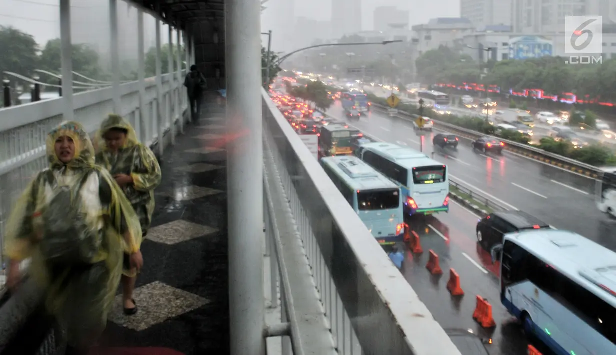 Pejalan kaki menggunakan jas hujan saat hujan deras mengguyur kawasan Gatot Soebroto, Jakarta, Senin (11/2). Badan Meteorologi, Klimatologi, dan Geofisika (BMKG) memprediksi puncak musim hujan terjadi hingga Februari 2019. (Merdeka.com/Iqbal Nugroho)