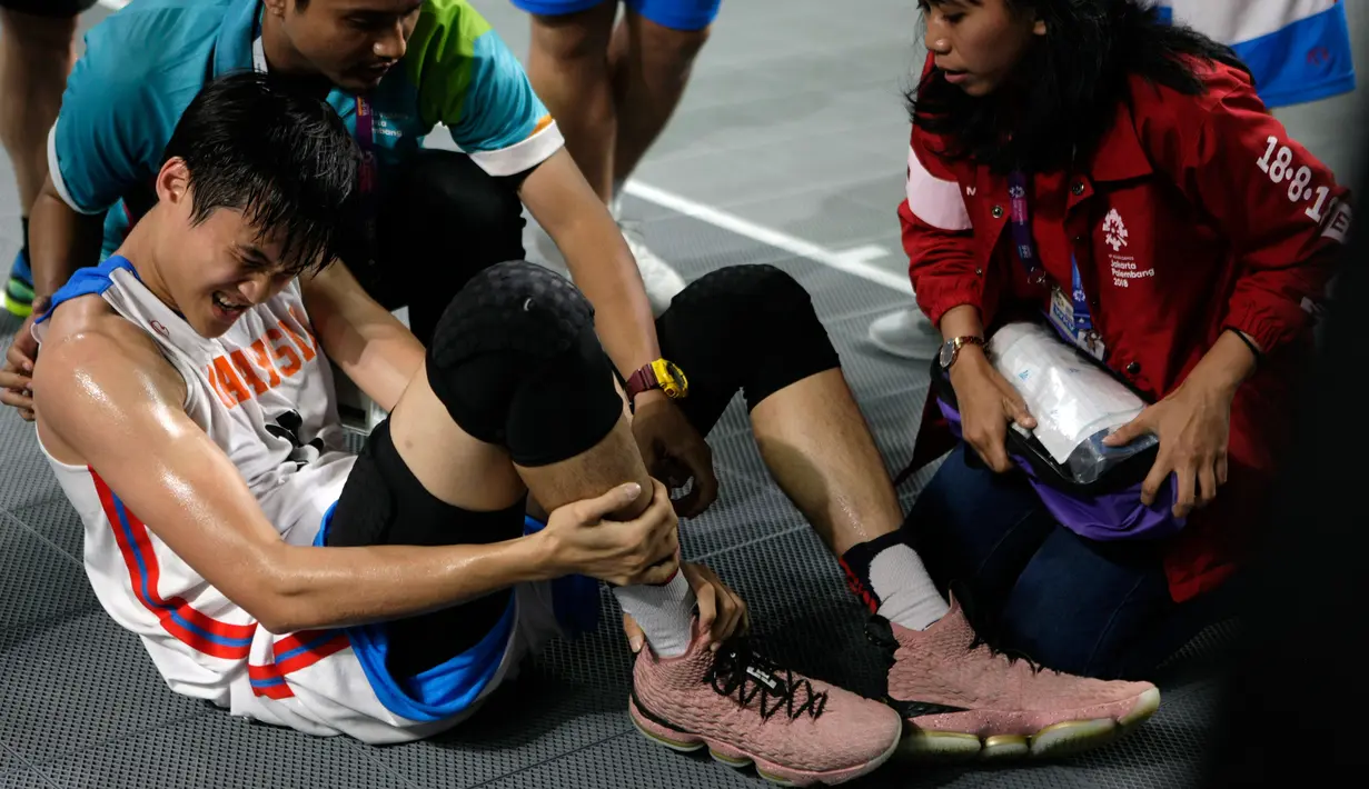 Atlet Malaysia, Yi Hou Wong mendapat perawatan tim medis usai laga antara Malaysia dan Iran di babak penyisihan Grup B basket putra 3x3 Asian Games 2018 di Jakarta, Rabu (22/8). (ANTARA FOTO/INASGOC/Ridhwan Siregar/Aa/18)