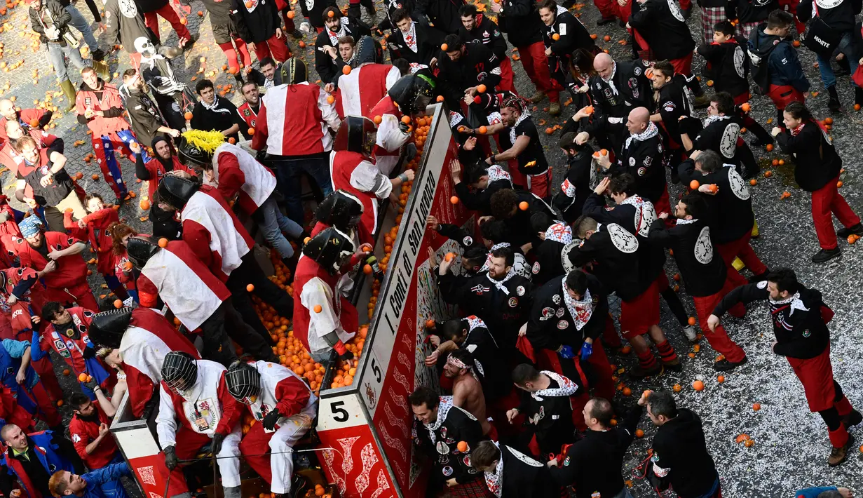 Keseruan festival "Battaglia delle Arance" (Perang Jeruk) di sebuah kota kecil di Provinsi Turin, Italia, Minggu (11/2). Penonton yang mengikuti festival ini menggunakan topi merah terang untuk membedakan dengan lainnya. (MIGUEL MEDINA/AFP)