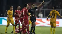 Wasit Thoriq Alkatiri memberikan kartu kuning kepada bek Bhayangkara FC, Sani Rizki, saat melawan Persija Jakarta pada laga Liga 1 di SUGBK, Jakarta, Jumat (23/3/2018). Kedua klub bermain imbang 0-0. (Bola.com/Vitalis Yogi Trisna)