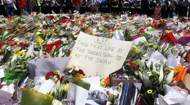 Sejumlah orang berdiri di balik pembatas tumpukan bunga di dekat Kafe Lindt, Sidney, Australia (16/12/2014). (REUTERS/David Gray)