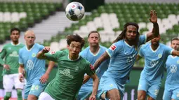 Pemain Werder Bremen, Yuya Osako, berebut bola dengan pemain Wolfsburg, Kevin Mbabu, pada laga Bundesliga di Weserstadion Minggu (7/6/2020). Werder Bremen takluk 0-1 dari Wolfsburg. (AFP/Patrik Stollarz)