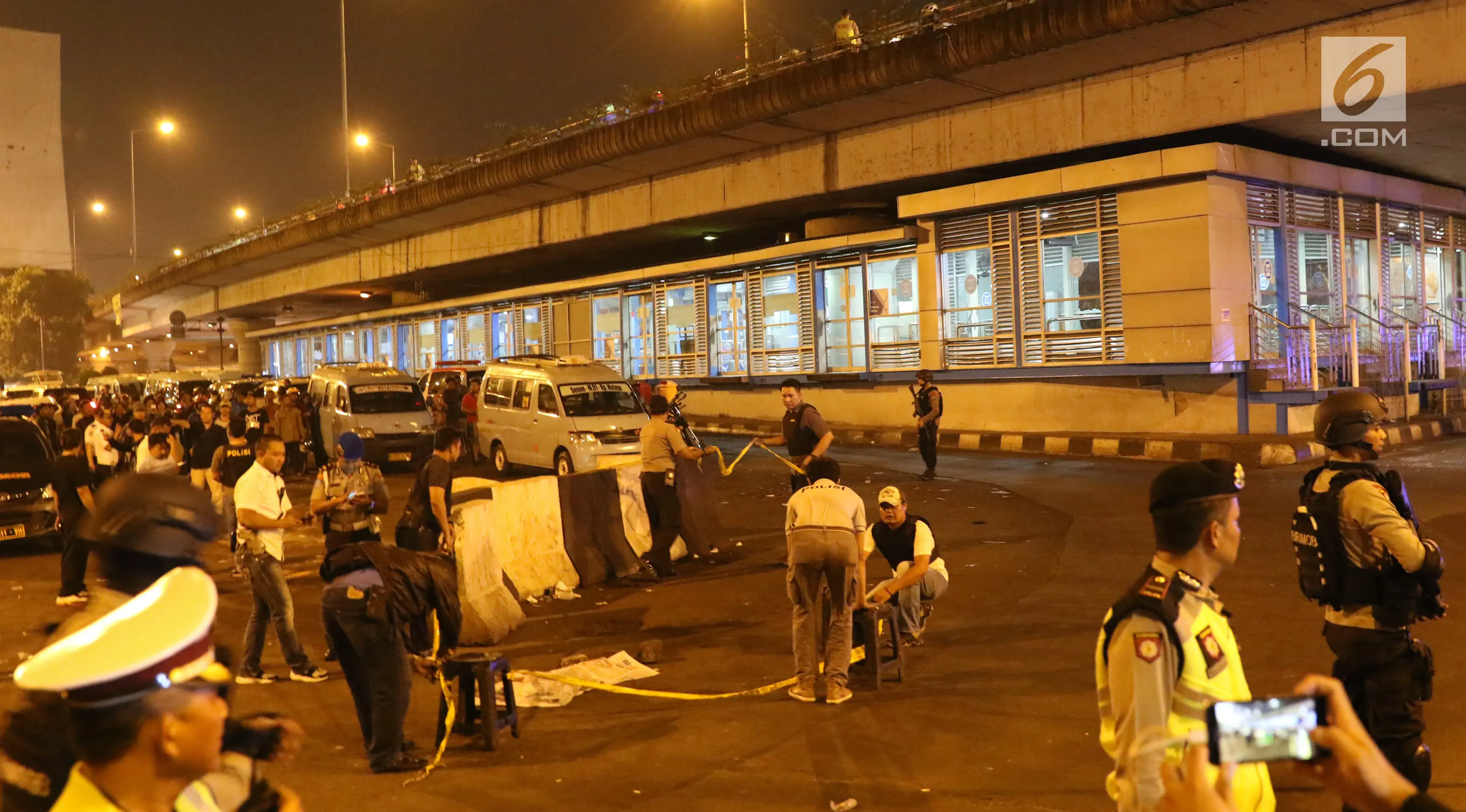Petugas memasang garis pembatas di lokasi terjadinya ledakan di sekitar Terminal Kampung Melayu, Jakarta, Rabu (24/5). Polisi belum bisa memastikan apakah tiga korban jiwa itu merupakan anggota polisi atau warga sipil. (Liputan6.com/Angga Yuniar)