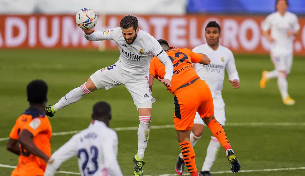 Pemain Real Madrid, Nacho, berebut bola dengan pemain Valencia, Maxi Gomez, pada laga Liga Spanyol di Stadion Alfredo Di Stefano, Minggu (14/2/2021). Real Madrid menang dengan skor 2-0. (AP/Manu Fernandez)