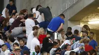Fans Inggris berusaha meloncat pagar pembatas antar-tribun di Stadion Velodrome, Marseille, Minggu (12/6/2016) dini hari WIB. Kerusuhan terjadi antara fans Rusia dan Inggris usai laga kedua negara yang berakhir imbang 1-1.  (Reuters/Kai Pfaffenbach) 