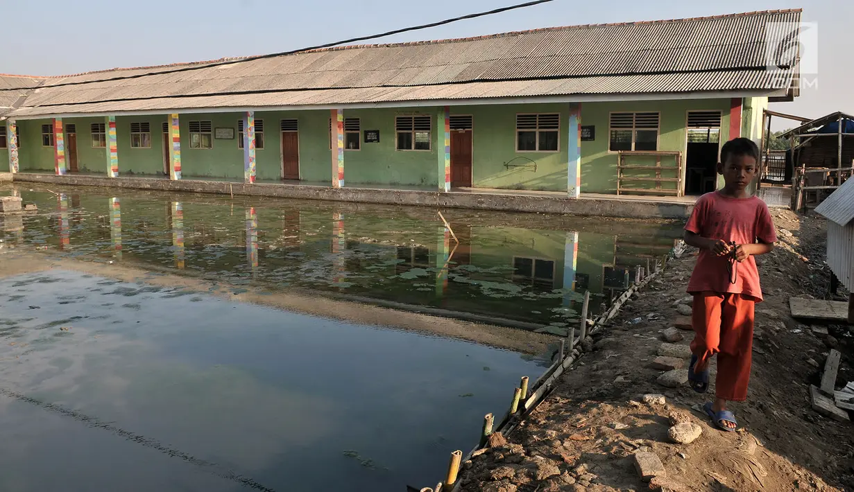 Seorang anak berada di depan gedung sekolah dasar yang rusak akibat abrasi di Kampung Beting, Desa Pantai Bahagia, Muara Gembong, Kabupaten Bekasi, Jawa Barat pada 28 Juli 2019. (merdeka.com/Iqbal S Nugroho)