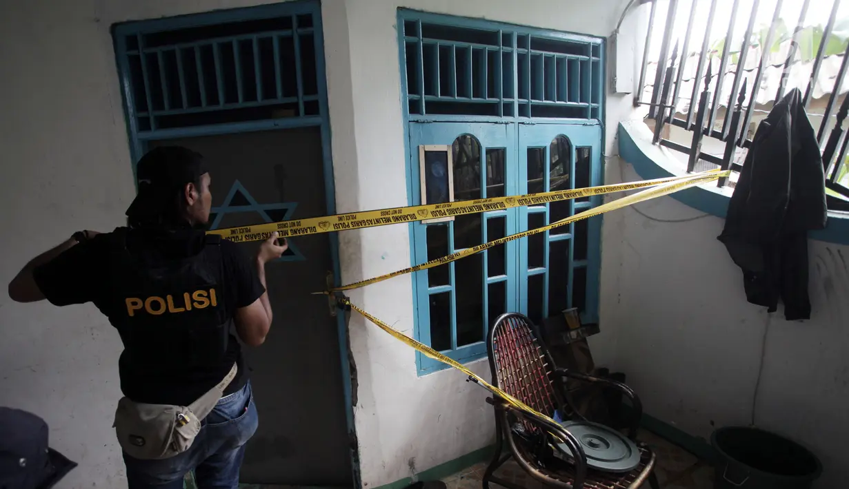 Petugas memasang garis polisi di sebuah rumah seusai penggerebekan peredaran narkoba di kawasan Kampung Ambon, Cengkarang, Jakarta, Rabu (24/1). Kampung Ambon sempat dikenal sebagai sarang narkotik di Jakarta. (Liputan6.com/Arya Manggala)