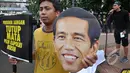 Massa dari Koalisi Untuk Reformasi Polri membawa topeng wajah Jokowi saat aksi di Car Free Day, Jakarta, Minggu (18/1/ 2015). (Liputan6.com/Miftahul Hayat)