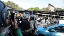 Pengendara yang melintas mengabadikan gambar bangkai Bus Transjakarta yang terbakar di Halte UI Salemba, Jakarta, Jumat (3/7). Bus Koridor V jurusan Ancol-Kampung Melayu tersebut terbakar sekitar pukul 08.30 WIB. (Liputan6.com/Faizal Fanani)