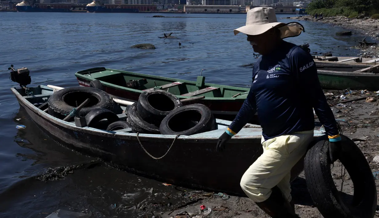 Nelayan memungut dan mengangkut ban bekas di pantai Pulau Pombeba, Teluk Guanabara, Rio de Janeiro, Brasil, Senin 17 Februari 2025. (Pablo PORCIUNCULA/AFP)