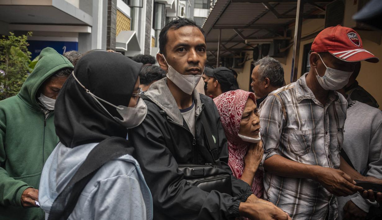 Keluarga dan kerabat korban tragedi Stadion Kanjuruhan menunggu di luar sebuah rumah sakit di Malang, Jawa Timur pada 2 Oktober 2022. Sedikitnya 174 orang tewas di stadion sepak bola Indonesia ketika ribuan penggemar tuan rumah yang marah menyerbu lapangan dan polisi menanggapi dengan gas air mata yang memicu desak-desakan, kata pihak berwenang pada 2 Oktober. (AFP/Juni Kriswanto)