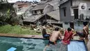 Anak-anak berenang di kolam yang berada di lokasi tanah longsor, Kemang Timur XI, Jakarta Selatan, Minggu (21/2/2021). Warga berharap pemerintah segera memperbaiki lokasi longsor agar banjir segera surut juga adanya bantuan sosial. (merdeka.com/Iqbal S. Nugroho)