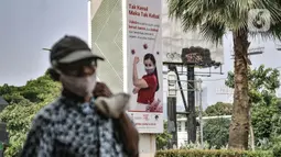 Warga melintas di dekat papan reklame sosialisasi vaksin Covid- di tiang pancang proyek monorel, Senayan, Jakarta, Selasa (17/11/2020). Papan reklame bertuliskan "Tak Kenal Maka Tak Kebal" mengimbau agar masyarakat tidak perlu takut terhadap suntikan Vaksin Covid-19. (merdeka.com/Iqbal S Nugroho)