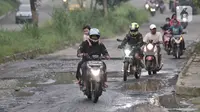 Pengendara motor melintasi jalan rusak dan berlubang di Jalan Tegar Beriman, Cibinong, Bogor, Minggu (31/5/2020). Sudah berbulan-bulan akses yang dikenal sebagai jalan Pemda Cibinong ini sangat memprihatinkan hingga sering menyebabkan kecelakaan terlebih saat musim hujan. (merdeka.com/Iqbal Nugroho)
