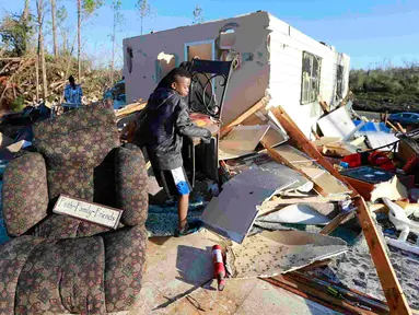 Jaquish Fox (10) membantu bibinya menyelamatkan barang yang masih bisa dipakai setelah tornado menghantam Holly Springs, Mississipi, Kamis (24/12). Badai tornado menerjang wilayah Amerika Serikat bagian selatan dan menewaskan 11 orang.  (REUTERS)