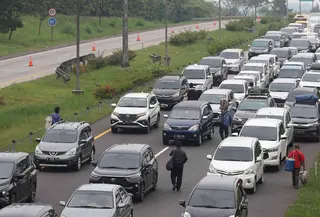 Pedagang menawarkan daganganya ke para pemudik di Jalan tol Cikopo - Palimanan KM 73, Purwakarta, Jawa Barat, Sabtu (30/4/2022). Padatnya arus lalu lintas ruas tol trans jawa, membuat pedagang asongan turun ke jalan. (Liputan6.com/Herman Zakharia)