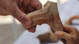 Seorang arkeolog menunjukkan sebuah stempel bertuliskan huruf Ibrani kuno yang ditemukan di sebuah situs penggalian di Yerusalem (22/7/2020). Tim arkeolog Israel menemukan pusat penyimpanan administratif berusia 2.700 tahun di Yerusalem. (Xinhua/Gil Cohen Magen)