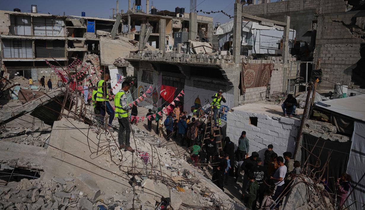 Reruntuhan bangunan berhias ucapan serta pesan Selamat Datang Ramadan yang menjadi simbol ketahanan warga Palestina di Gaza. Tampak dalam foto, warga Palestina menggantungkan hiasan Ramadan di samping reruntuhan rumah yang hancur di Khan Younis, Jalur Gaza selatan, Minggu 15 Februari 2026. (AP Photo/Abdel Kareem Hana)