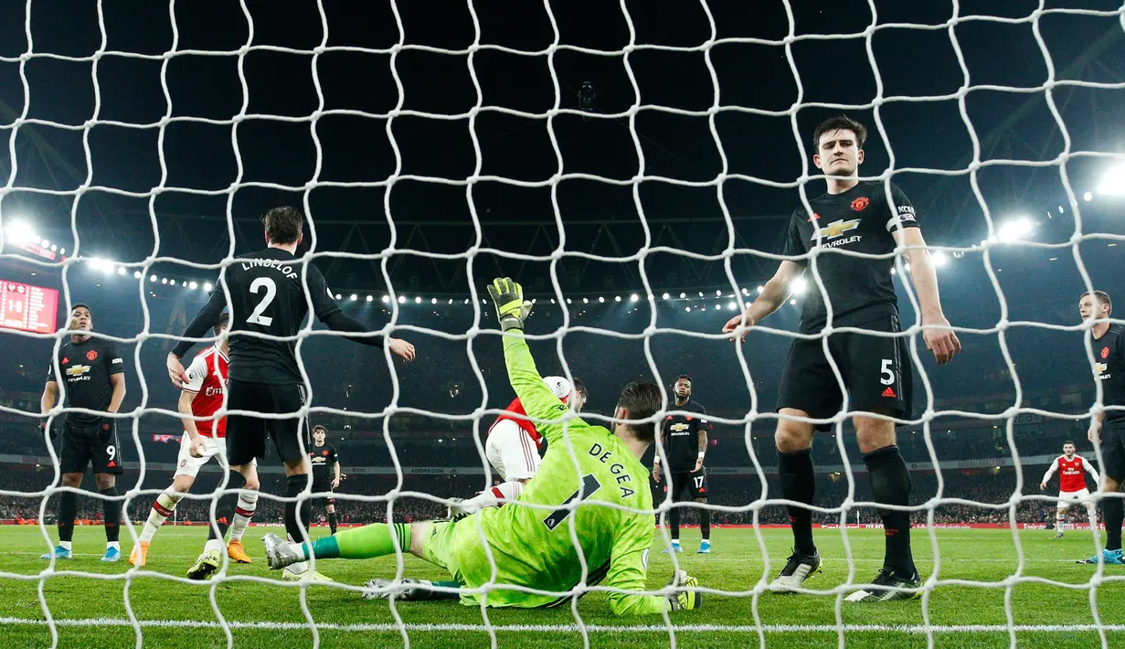 Kiper Manchester United David de Gea (tengah) berbaring di tanah saat pemain Arsenal Sokratis Papastathopoulos mencetak gol ke gawangnya pada pertandingan lanjutan Liga Inggris di Emirates Stadium, London, Rabu (1/1/2020). Arsenal menang 2-0. (AP Photo/Matt Dunham)