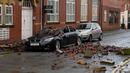 Reruntuhan atap apartemen yang runtuh karena angin kencang tampak berserakan dan menyebabkan sebuah mobil yang diparkir rusak parah di Leigh, barat laut Inggris, Rabu (18/11). (AFP PHOTO/Paul Ellis)