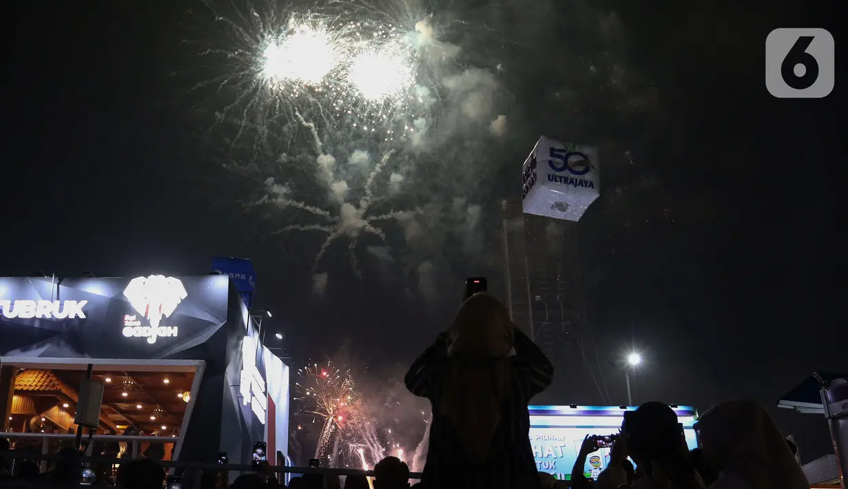 Pengunjung menyaksikan pesta kembang api di langit saat Jakarta Fair ke-53 atau Pekan Raya Jakarta (PRJ) di JiExpo Kemayoran, Jakarta Pusat, Selasa (21/6/2022) malam. Pesta kembang api menggelegar di kawasan PRJ bertepatan dengan HUT Jakarta yang jatuh pada besok, 22 Juni 2022. (Liputan6.com/Herman Zakharia)