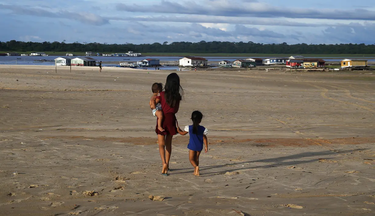 Anak-anak berjalan di daerah yang terkena dampak kekeringan dekat Sungai Solimões, Tefe, Amazonas, Brasil, Rabu (19/10/2022). Gumuk pasir yang muncul menjadi penghambat kapal besar yang datang membawa pasokan makanan warga, hal ini membuat 680 keluarga kesulitan mendapat makanan, mengakses air minum dan tidak dapat mencapai markas kotamadya untuk membeli makanan. (AP Photo/Edmar Barros)