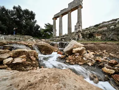 Air mengalir melalui reruntuhan di lokasi kota kuno Cyrene (Shahhat) Yunani-Romawi di Libya timur, sekitar 60(37 mil) barat Derna setelah banjir dahsyat, pada 21 September 2023. (Ozan KOSE / AFP)