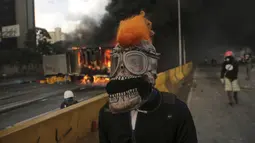 Demonstran anti-pemerintah di Venezuela mengenakan masker saat menggelar aksi di Caracas, Venezuela, Sabtu (26/5). Gelombang protes disebabkan oleh keputusan Mahkamah Agung untuk mengambil fungsi parlemen negara yang dikuasai oposisi. (AP Photo)  