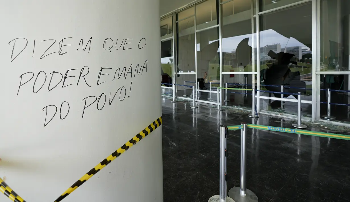 Ungkapan Portugis "Mereka mengatakan bahwa kekuasaan berasal dari rakyat" menutupi permukaan di luar Senat sehari setelah Gedung Kongres diserbu oleh pendukung mantan Presiden Brasil Jair Bolsonaro di Brasilia, Senin (9/1/2023). Para pengunjuk rasa juga menyerbu kantor kepresidenan, Istana Planalto, dan Mahkamah Agung. (AP Photo/Eraldo Peres)