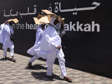 Umat muslim menggunakan karton untuk melindungi diri dari sengatan matahari saat berjalan di jalanan di kota Makkah, Arab Saudi, pada 2 Juni 2025. (HAZEM BADER/AFP)