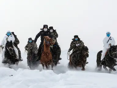 Petugas polisi mengenakan masker wajah berusaha melintasi jalanan bersalju saat akan melakukan sosialisasi tentang bahaya virus COVID-19 sekaligus memeriksa kondisi kesehatan warga daerah terpencil di Altay, Wilayah Xinjiang, China (19/2/2020). (AFP/STR)