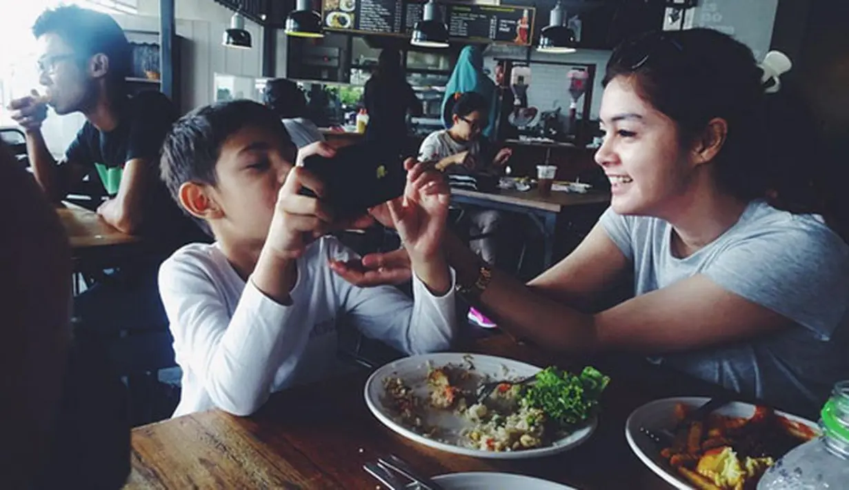 Seperti yang terlihat dalam foto ini, dengan senyum semringah Biby menyuapkan makanan untuk Arsen yang sedang asyik bermain ponsel pintarnya. Keduanya tampak sedang berada di sebuah restoran. (Instagram/rifkybalweel)
