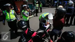 Polisi mengisi surat tilang untuk pengendara motor pada Operasi Progo Patuh di Jl Malioboro, Yogyakarta, Rabu (18/5). Operasi Patuh di gelar secara serempak di seluruh Indonesia hingga 29 Mei 2016. (Liputan6.com/Boy Harjanto)