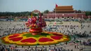 Para wisatawan berjalan di dekat "keranjang bunga" di Lapangan Tian'anmen di Beijing, ibu kota China (24/9/2020). Dekorasi setinggi 18 meter berbentuk keranjang bunga itu ditempatkan di tengah Lapangan Tian'anmen untuk menyambut masa libur Hari Nasional China mendatang. (Xinhua/Chen Zhonghao)