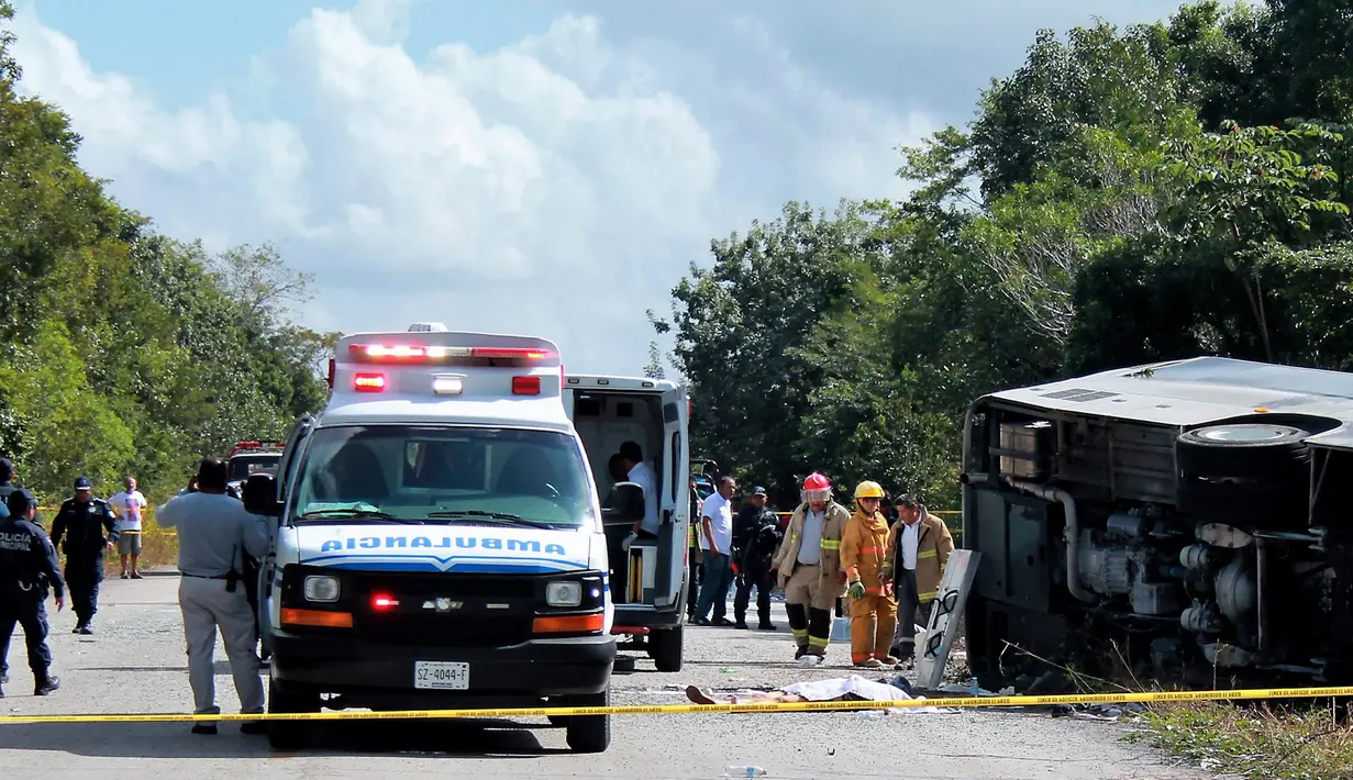 Jasad penumpang tergeletak di dekat bus wisata yang terbalik di jalan raya Mahahual di Quintana Roo, Meksiko, Selasa (19/12). Hingga kini, polisi masih menyelidiki penyebab terjadinya kecelakaan. (Novedades de Quintana Roo via AP)