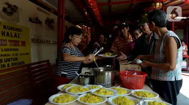 Pengurus Vihara Kim Tek Ie menyiapkan menu makan siang untuk pembeli warung nasi kuning Podjok Halal di Petak Sembilan, Jakarta, Selasa (24/12/2019). Warung Podjok Halal menjual nasi beserta lauk pauk dengan harga Rp 3.000. (merdeka.com/Imam Buhori)