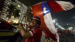 Salah satu suporter terus mengibarkan bendera kebangsaan Chili saat selebrasi keberhasilan La Roja lolos ke zona 16 besar Piala Dunia 2014 di sepanjang pantai Copacabana, Rio de Janeiro, Brasil, (19/6/2014). (REUTERS/Lucas Landau)