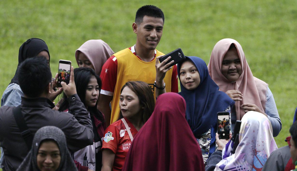Pemain Arema FC, Hanif Sjahbandi, foto bersama dengan fans usai sesi latihan di Stadion Gajayana, Malang, Kamis (11/4). Setelah sesi latihan, pemain Arema FC melayani permintaan fans untuk foto bersama. (Bola.com/Yoppy Renato)