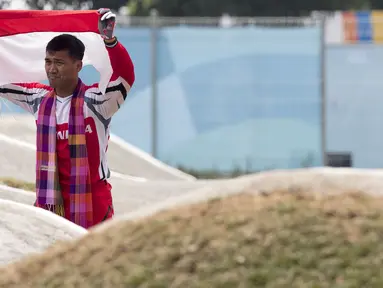 Pebalap sepeda BMX Indonesia, I Gusti Bagus Saputra, mengibarkan bendera usai berlaga pada Asian Games di Pulomas BMX Center, Jakarta, Sabtu (25/8/2018). Bagus Saputra meraih medali perak dengan catatan waktu 34,314 detik. (Bola.com/Peksi Cahyo)