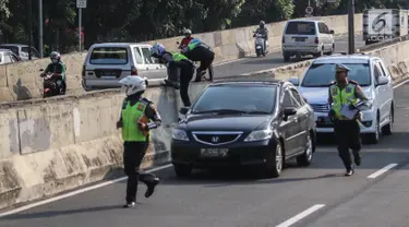 Petugas polisi lalu lintas (polantas) mengejar pengendara sepeda motor  yang melintasi JLNT Kampung Melayu-Tanah Abang, Jakarta, Selasa (25/7). Sepeda motor dilarang melintas di JLNT tersebut karena merupakan jalur cepat. (Liputan6.com/Faizal Fanani)