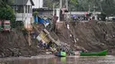 Kerusakan tersebut mengganggu mobilitas warga dan arus lalu lintas. Tampak dalam foto, warga terdampak banjir menaiki perahu untuk menyeberangi Sungai Peusangan di Kuta Blang, Kabupaten Bireuen, Provinsi Aceh, Selasa 9 Desember 2025. (CHAIDEER MAHYUDDIN/AFP)