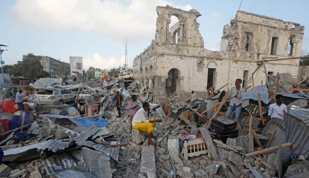 Warga berkumpul di bangunan yang hancur menyusul serangan bom mobil kembar di Ibu Kota Mogadishu, Somalia, Sabtu (24/2). Dua ledakan bom mobil mengguncang Mogadishu pada Jumat, 23 Februari 2018 malam. (AP Photo/Farah Abdi Warsameh)