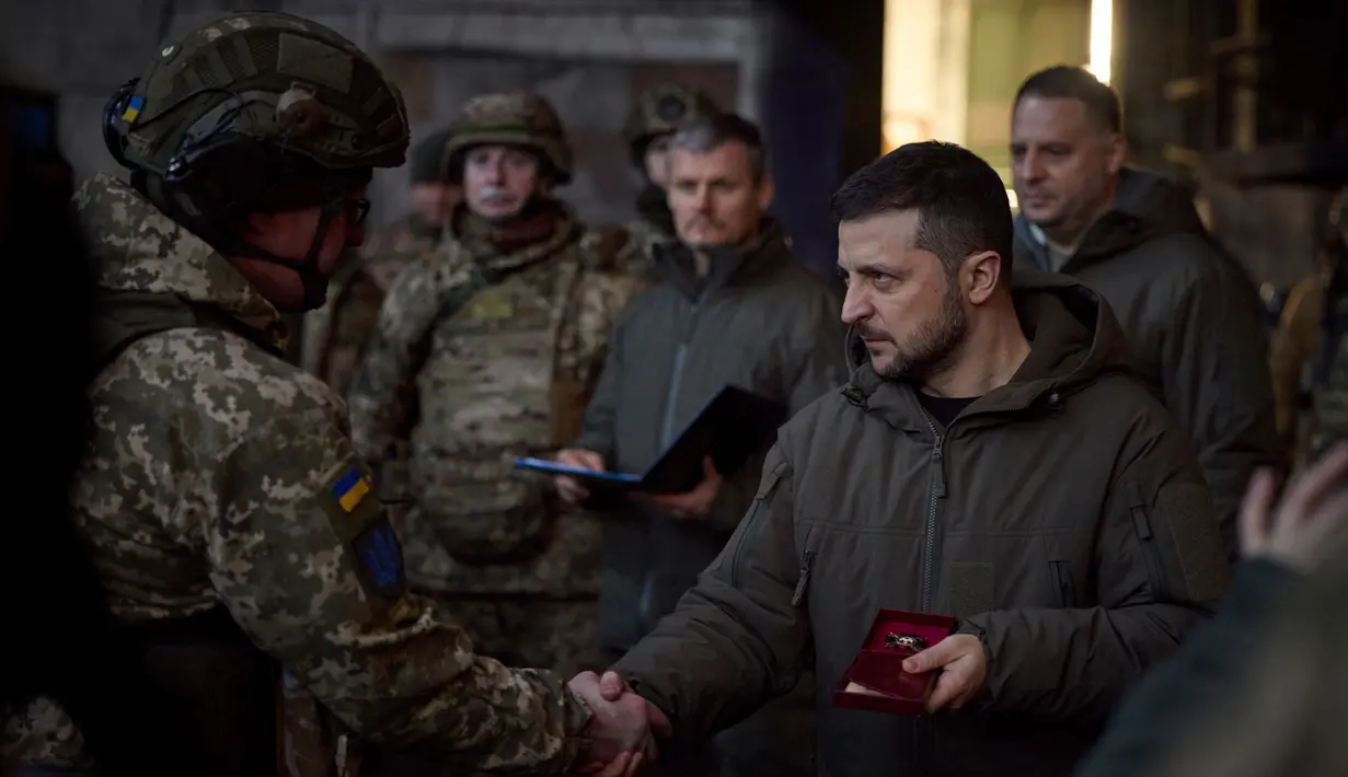 Presiden Ukraina Volodymyr Zelenskyy (kanan) memberikan penghargaan kepada seorang tentara di lokasi pertempuran terberat melawan Rusia di Bakhmut, Ukraina, 20 Desember 2022. Selama di Bakhmut, Zelenskyy membagikan penghargaan kepada prajurit Ukraina. (Ukrainian Presidential Press Office via AP)
