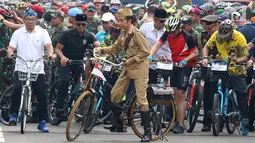 Presiden Joko Widodo atau Jokowi (tengah) didampingi Gubernur Jawa Barat Ridwan Kamil (kiri) saat mengikuti Bandung Lautan Sepeda, Sabtu (10/11). Jokowi berpakaian khas Sutomo atau Bung Tomo dalam kegiatan tersebut. (Liputan6.com/Angga Yuniar)