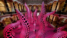 Pengunjung berjalan melewati instalasi seni berjudul 'A bouquet of love I saw in the universe' karya seniman kontemporer Jepang Yayoi Kusama dalam pameran Yayoi Kusama: A Retrospective di Atrium Martin Gropius Bau, Berlin, Jerman, Selasa (19/5/2021). (John MACDOUGALL/AFP)
