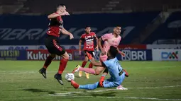 Kiper Madura United, Muhammad Ridho (kanan) berusaha menghalau bola tendangan pemain Bali United, Ilija Spasojevic dalam laga pekan ke-16 BRI Liga 1 2021/2022 di Stadion Sultan Agung, Bantul, Kamis (09/12/2021). (Bola.com/Bagaskara Lazuardi)