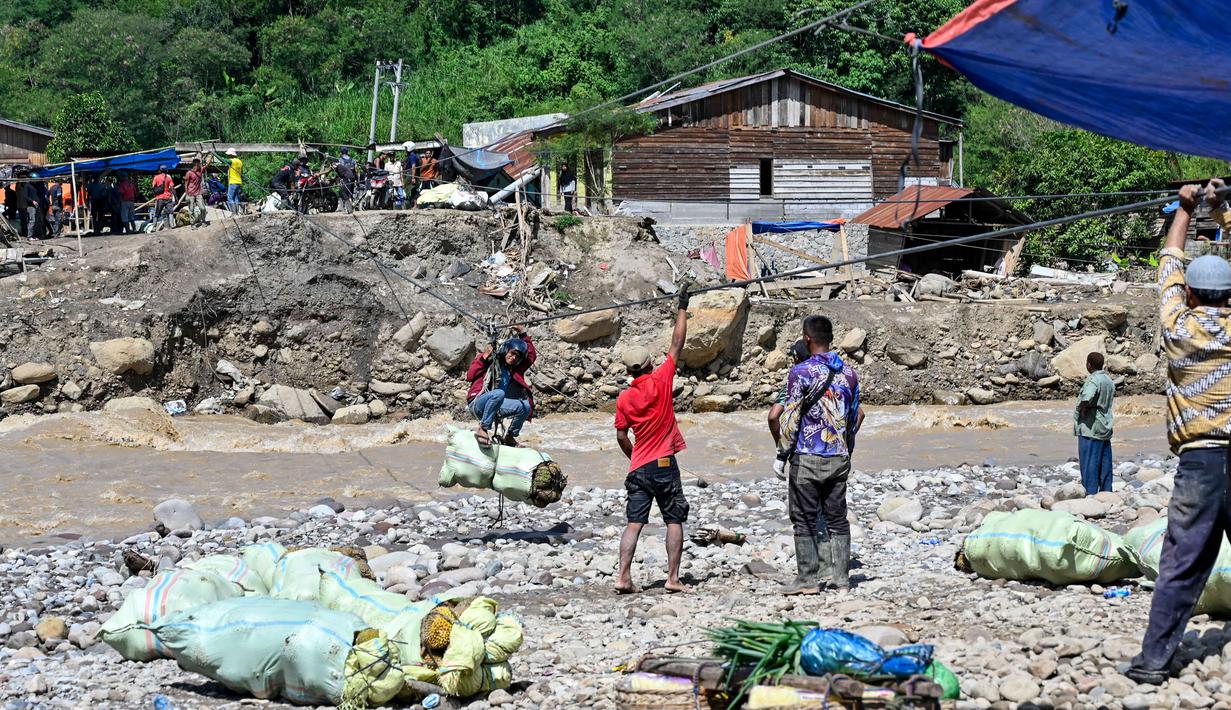 Hingga awal Januari 2026, warga Kecamatan Ketol di Aceh Tengah belum bisa menikmati akses jalan yang layak. Tampak dalam foto, warga menggunakan tali untuk menyeberangi sungai setelah banjir bandang yang menghancurkan desa-desa di sekitarnya di Ketol, provinsi Aceh, pada Selasa 6 Januari 2026. (CHAIDEER MAHYUDDIN/AFP)