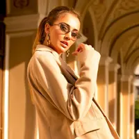 Seorang perempuan mengenakan jas berwarna beige berdiri di sebuah lorong (Foto Dok: Freepik/diana_mironenko).