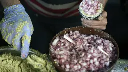 Seorang warga Palestina membuat falafel isi bawang bombay, makanan yang disantap saat berbuka puasa, selama bulan suci Ramadhan di pusat kota Hebron di Tepi Barat yang diduduki (9/4/2022). Falafel adalah sebuah makanan Timur Tengah. (AFP/Hazem Bader)